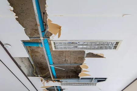 Water damaged ceiling with exposed water pipes