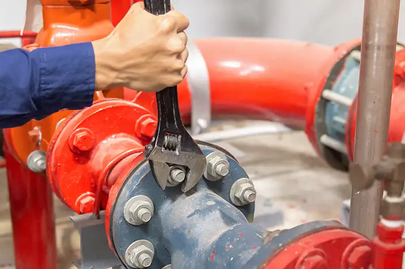 Person fixing flanges on large red pipes