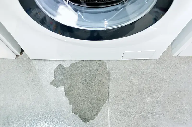 Water puddled in front of a washing machine